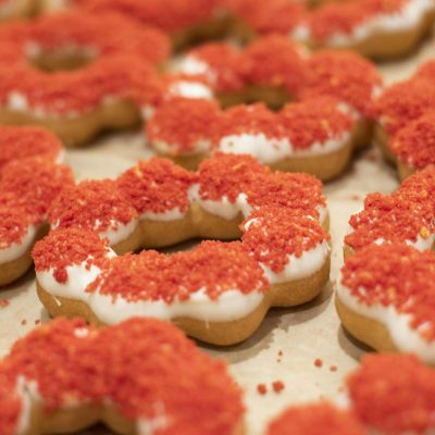 Close-up photo of mochi donuts topped with vibrant red sprinkles, showcasing intricate detail.